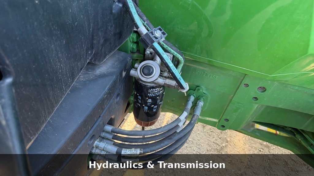 Close-up of hydraulic lines and transmission filter housing on a John Deere 6110M