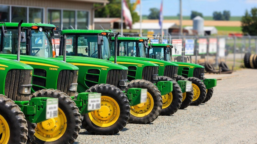 Used John Deere tractors lined up at a dealer lot for resale - Vehicle Review Hub