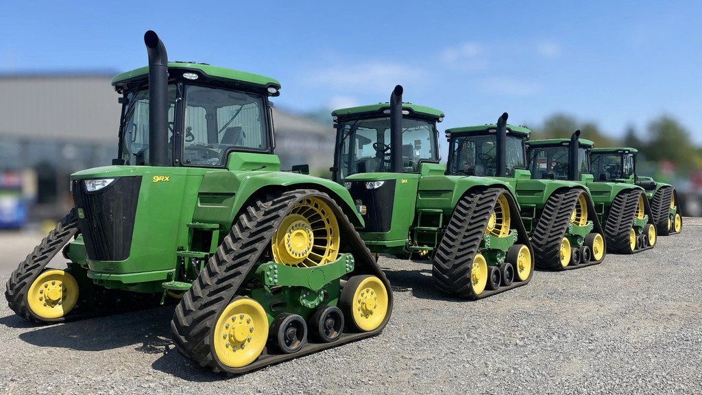 John Deere 9RX 590 ownership cost: four-track tractors on a dealership sales lot showing resale value - Vehicle Review Hub